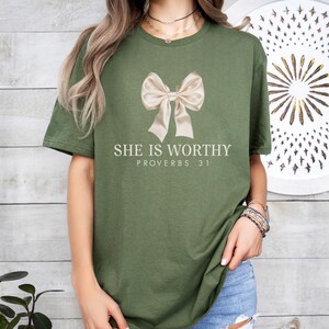 May include: A green t-shirt with a white bow and the text "She is worthy Proverbs 31" printed on the front.