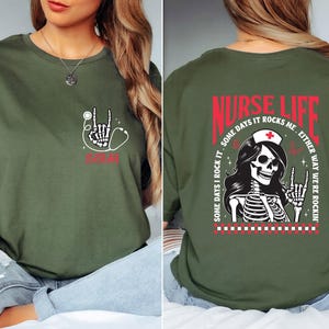 May include: Olive green t-shirt with a skeleton hand and stethoscope graphic. The front of the shirt has the word "NURSE" in red. The back of the shirt has the words "NURSE LIFE" and a skeleton nurse graphic.