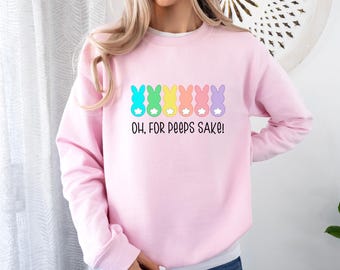 Puede incluir: Una sudadera rosa con una fila de coloridos peeps de Pascua en forma de conejo y el texto "Oh, for peeps sake!"