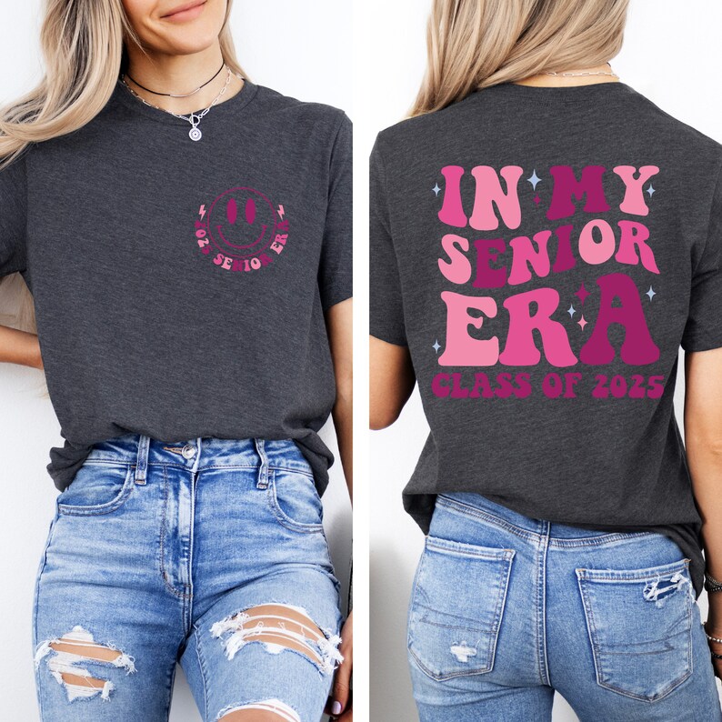 Puede incluir: Una camiseta gris oscuro con un gr&aacute;fico de una cara sonriente rosa en la parte delantera y el texto "In My Senior Era Class of 2025" en la parte posterior.