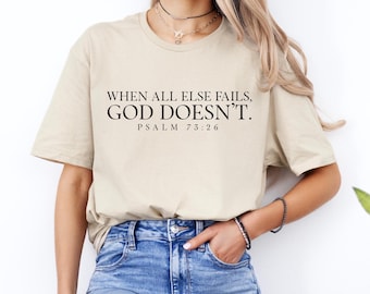May include: A beige t-shirt with the text "WHEN ALL ELSE FAILS, GOD DOESN'T." and "PSALM 73:26" printed in black.