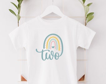 May include: White t-shirt with a rainbow design and the word "two" in a script font.