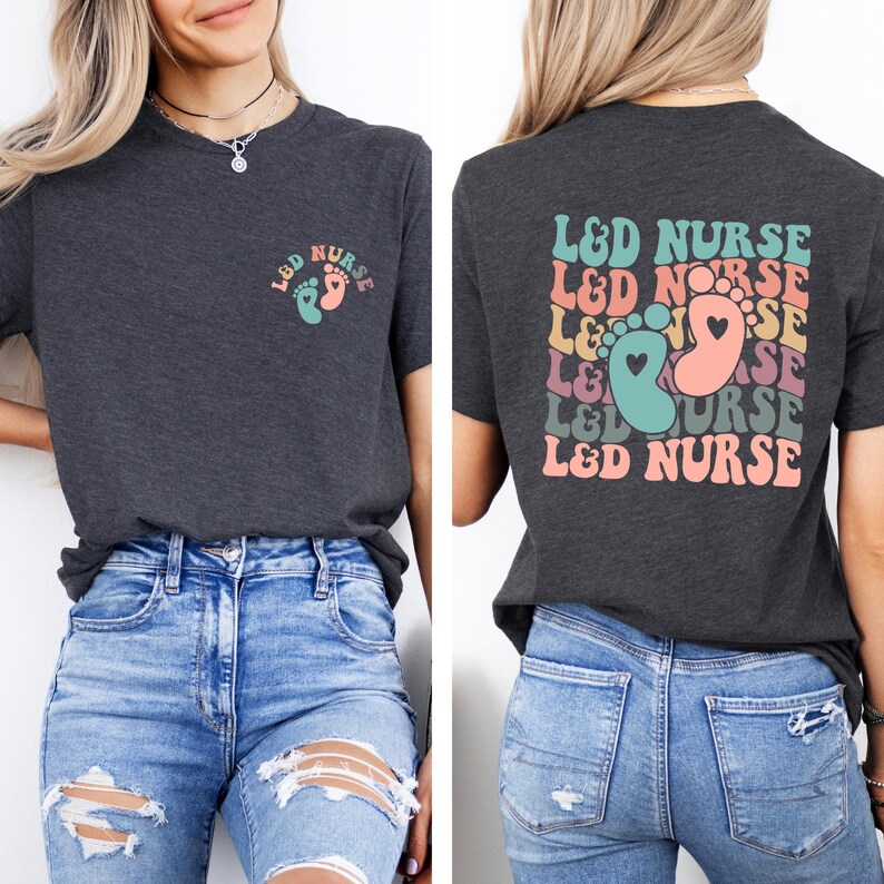 May include: A dark grey t-shirt with the text "L&D NURSE" repeated in a rainbow pattern on the back. The front of the shirt has a small design of two footprints with a heart in the center.
