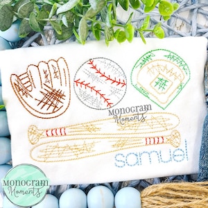May include: White baseball-themed shirt with embroidered baseball glove, baseball, baseball field, and bats. The name "Samuel" is embroidered in blue. The shirt also features the text "Monogram Moments".