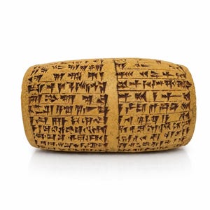 Può includere: Una tavoletta di argilla rettangolare color beige con scrittura cuneiforme. La tavoletta è di colore marrone chiaro con segni marrone scuro. Il testo copre l'intera superficie della tavoletta, con una linea verticale.