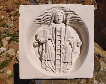 May include: A white plaster relief sculpture of a person holding a book and a ladder. The person is wearing a robe and has long hair. The sculpture is set against a white background.