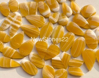 以下が含まれることがあります： 様々な雫型と楕円形の黄白色の縞模様のアゲートカボションの集まり。石は研磨されており、滑らかで光沢のある仕上がりです。