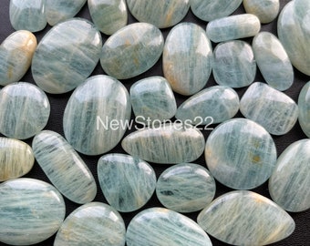 May include: A collection of smooth, light blue aquamarine stones with a striated pattern. The stones are oval shaped and have a translucent appearance.