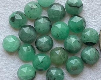 May include: A collection of 20 faceted green gemstone cabochons. The cabochons are round and have a polished, smooth surface. They are a light to medium green color with some darker green inclusions.