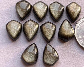 Pode incluir: Dez cabochões de pedra preciosa dourados e pretos em forma de lágrima com acabamento facetado.