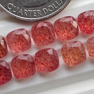May include: Ten square-shaped, translucent red gemstones with a speckled pattern. The gemstones are approximately 1/2 inch in size.