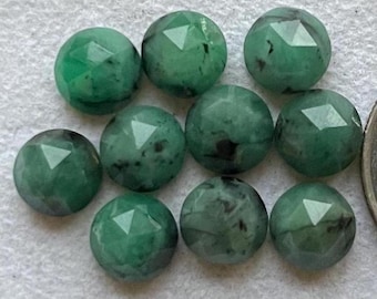 May include: Ten faceted green gemstone cabochons with black inclusions. The cabochons are round and have a polished finish.