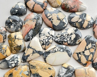 May include: A collection of 15 natural stone cabochons in various shapes and sizes. The stones are a mix of beige, brown, black, and white with a mottled pattern.