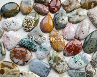 May include: A collection of 22 polished agate cabochons in various colors and patterns, including brown, white, gray, green, and red. The stones are smooth and have a natural, organic look.