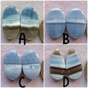 May include: Four pairs of polished opal gemstones. Each pair features a unique pattern of blue, white, and brown hues. The gemstones are oval and teardrop shaped, with a polished, glossy finish. The gemstones are displayed next to a coin for size reference.