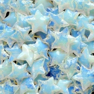 May include: A close-up image of a pile of iridescent blue star-shaped glass pieces. The glass is translucent and has a slightly milky appearance.