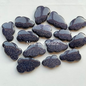 Könnte beinhalten: Eine Sammlung von 14 dunkelblauen, glitzernden, wolkenförmigen Cabochons. Die Cabochons bestehen aus einem glitzernden Material und haben eine glatte, polierte Oberfläche.