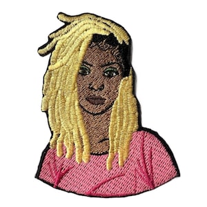 May include: Embroidered iron-on patch featuring a woman with blonde dreadlocks and a pink shirt.