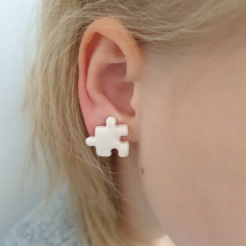 Marble white puzzle piece earrings in non pierced ear of a 6 year old blonde girl.