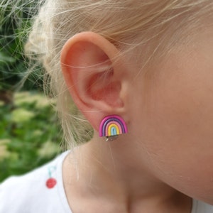 Rainbow earrings for non pierced ears in blonde girls right ear.