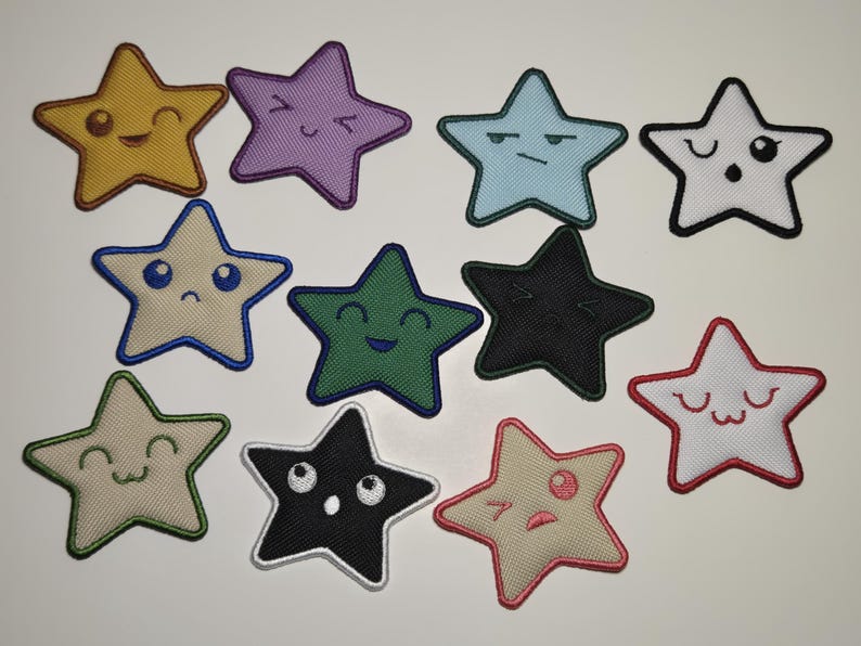 May include: A collection of eleven star-shaped embroidered patches with various facial expressions. The patches are in a variety of colors, including yellow, purple, blue, white, green, and black. Each star has a black outline.