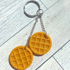 May include: A keychain with two round, brown waffle-shaped charms attached to a silver chain and ring.