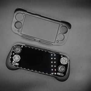 May include: Two handheld gaming consoles, one in a gray protective case and the other with a black screen and controls. The consoles are set against a dark gray background, showcasing their design and features.