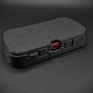 May include: A black, rectangular case with a textured surface. The case has a red accent and the text "POP" printed on the top.