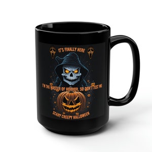 May include: Black coffee mug with a Halloween design featuring a skull with a pumpkin in front of it. The text reads "It's finally here I'm the master of horror, so don't test me Scary Creepy Halloween".