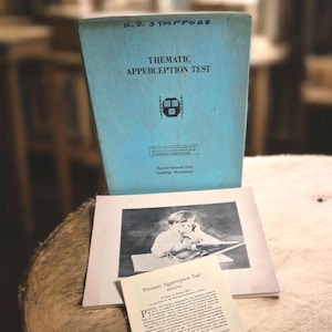 Puede incluir: Un juego vintage de la "Prueba de Apercepción Temática" de H.J. Stafford. El juego incluye un libro azul claro con el título, una imagen en blanco y negro y un manual. Los artículos están sobre una mesa de madera.