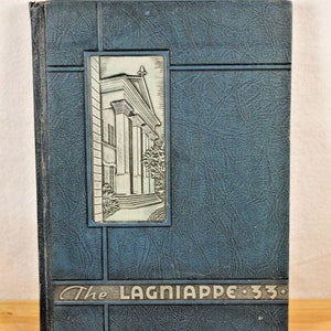 May include: A vintage blue yearbook titled "The Lagniappe '33." The cover features a textured design with a rectangular inset showcasing a detailed illustration of a building with columns. The book's title is in a stylized font.