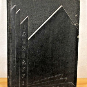 May include: Black hardcover book with a white embossed design on the front cover. The design features a stylized building with the word "LAGNAPPE" written vertically on the left side. The year "1931" is embossed at the bottom of the cover.