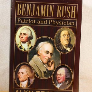 May include: A book titled "Benjamin Rush Patriot and Physician" by Alyn Brodsky. The cover features a portrait of Benjamin Rush surrounded by portraits of other historical figures.