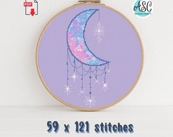May include: A cross-stitch design of a crescent moon in shades of blue, pink, and purple, with dangling stars, set against a lavender background. The design is framed in a wooden hoop. The text "59 x 121 stitches" is at the bottom.