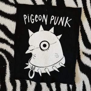 May include: Black and white iron-on patch featuring a cartoon pigeon wearing a spiked collar. The text "PIGEON PUNK" is printed above the pigeon.