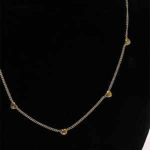 May include: A gold chain necklace with four small heart-shaped charms.