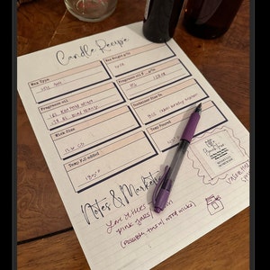 May include: A handwritten candle recipe on a lined paper, with fields for wax type, fragrance oil, wick size, and temperature. A purple pen rests on the paper, with notes about pink jars and wood wicks. A small jar and a bottle are in the background.