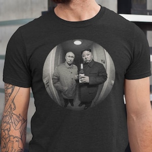 May include: A black t-shirt with a fisheye lens photo of two men standing in a hallway. The men are wearing suits and one is holding a bottle of alcohol.