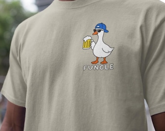 May include: A beige short-sleeved t-shirt featuring a graphic of a white goose wearing a blue baseball cap and black sunglasses while holding a mug of beer. Below the goose, the word "FUNCLE" is printed in white capital letters.