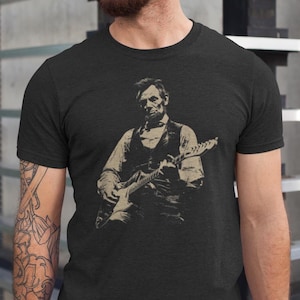 Peut inclure: T-shirt gris fonc&eacute; avec une illustration s&eacute;pia d'Abraham Lincoln jouant de la guitare &eacute;lectrique. L'image montre Lincoln en gilet et chemise, tenant la guitare. Le t-shirt a un col rond et des manches courtes.