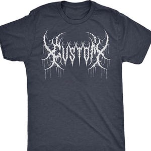 May include: A navy blue t-shirt featuring the white word "KUSTOM" in a gothic, stylized font. The design has a dripping effect, adding a unique visual element to the apparel. The shirt is a classic crew neck style.