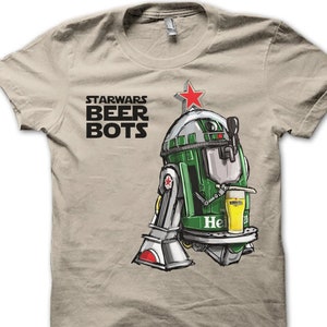 Könnte beinhalten: Ein beiges T-Shirt mit einem grünen Roboter, der ein Glas Bier hält. Der Roboter ist ein Star Wars-Charakter und der Text "STAR WARS BEER BOTS" ist auf dem T-Shirt aufgedruckt.