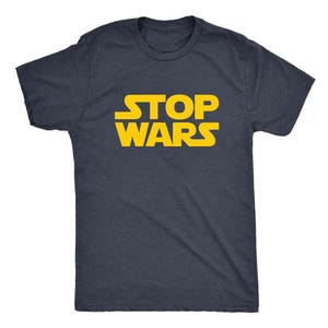 Op de afbeelding: Een donkergrijs gemêleerd T-shirt met korte mouwen en de tekst STOP WARS in een vetgedrukt, geel, gestileerd lettertype op de borst. Het kledingstuk heeft een ronde hals en een standaard pasvorm, met een eenvoudig ontwerp en opvallende letters.