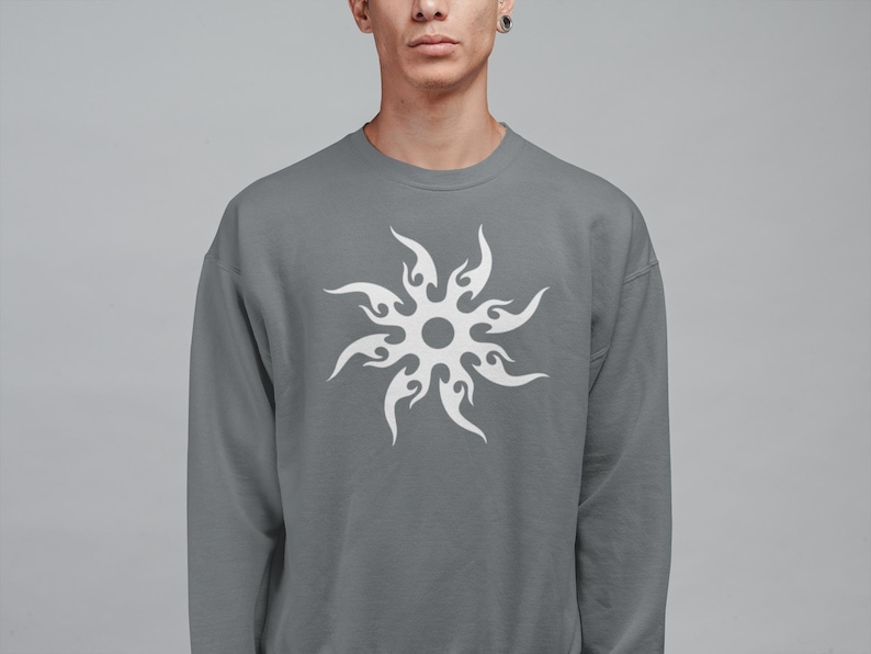 Puede incluir: Una sudadera gris con un dise&ntilde;o de sol blanco. La sudadera de cuello redondo es de color liso y tiene mangas largas. El dise&ntilde;o del sol est&aacute; centrado en la parte delantera de la sudadera.