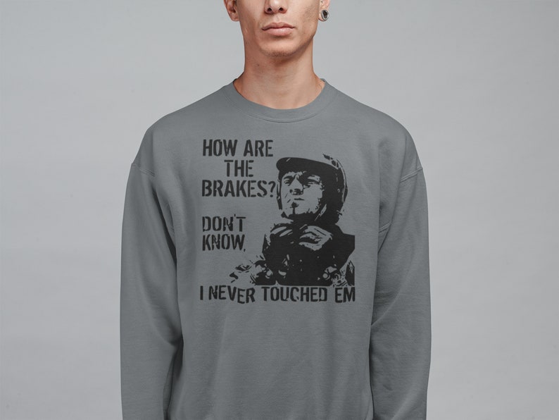 May include: A grey sweatshirt with a black graphic print of a man in a racing helmet. The text on the sweatshirt reads "How are the brakes? Don't know, I never touched 'em."