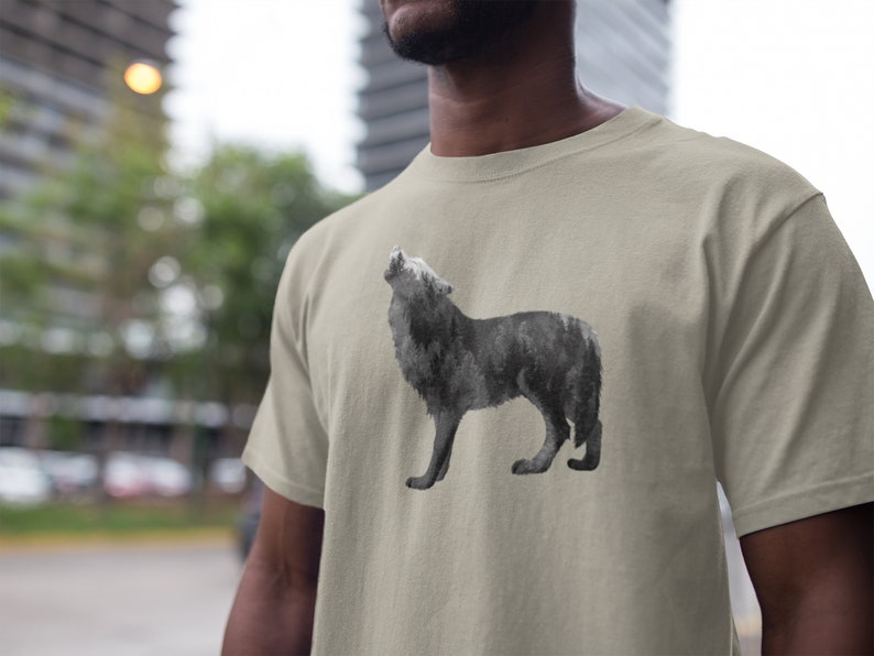 May include: A light beige t-shirt with a black and white wolf howling graphic. The wolf is made up of a forest scene.