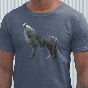 May include: A dark blue t-shirt with a watercolor-style image of a wolf howling at the moon. The wolf is in shades of gray and black.