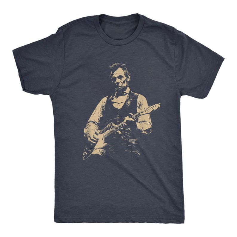 Peut inclure: T-shirt bleu marine avec une illustration s&eacute;pia d'une personne jouant de la guitare &eacute;lectrique. L'illustration repr&eacute;sente une personne en gilet et chemise, tenant la guitare. Le t-shirt est &agrave; col rond.