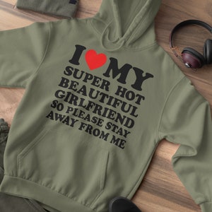 May include: A green hooded sweatshirt with the text "I love my super hot beautiful girlfriend so please stay away from me" in black lettering and a red heart.