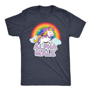 May include: Dark navy blue t-shirt featuring a cartoon unicorn with a rainbow, clouds, and the text "ALPHA MALE" in pink and white. The unicorn has a yellow horn, purple and yellow mane, and a heart on its side.